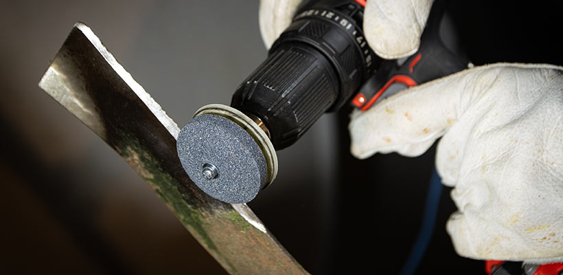 Close up shot of sharpening a lawn mower blade.