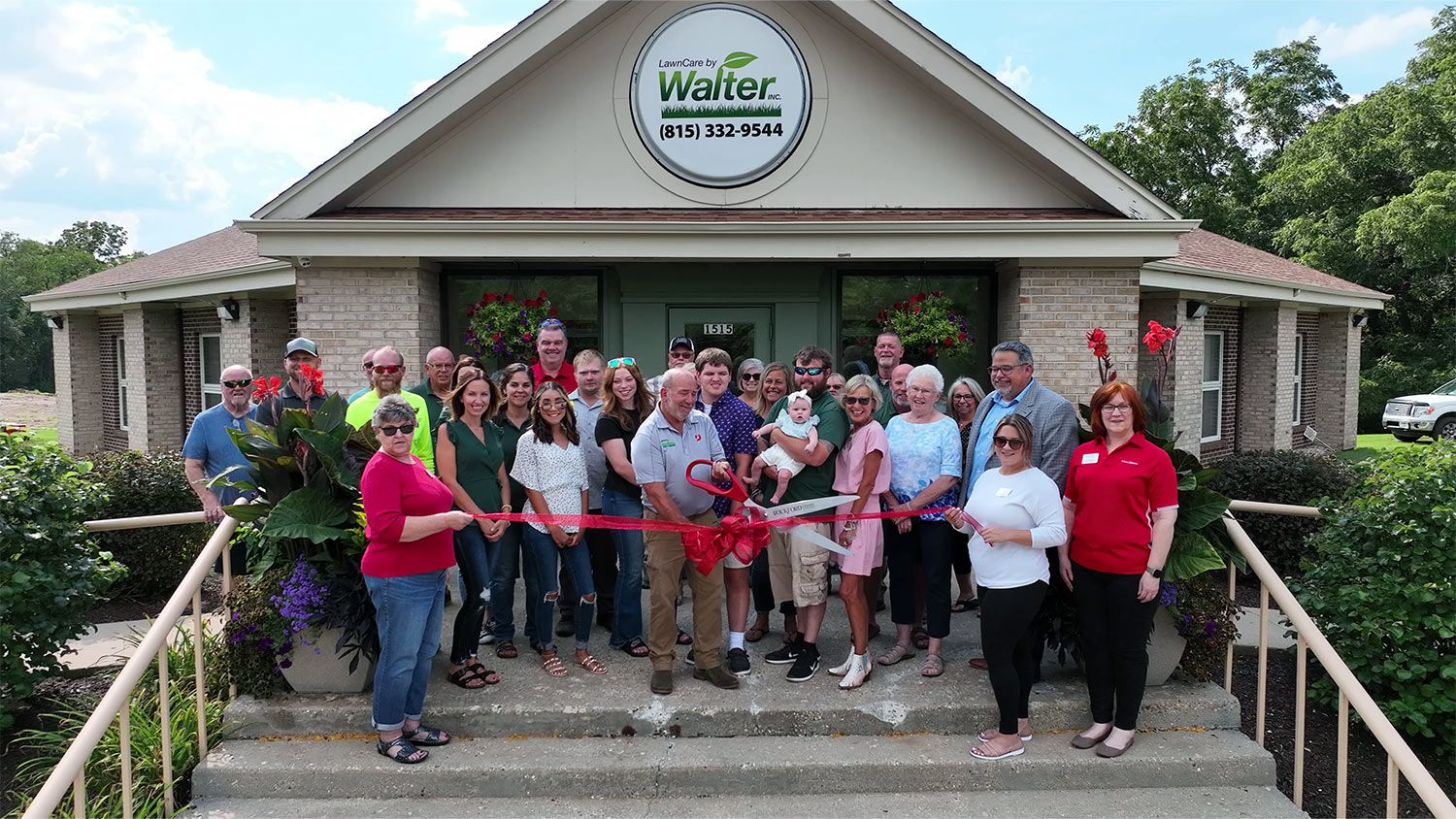 With the entire LawnCare by Walter team behind him, Mark Walter cuts the ribbon at 1515 Meridian Road in Rockford, Illinois.